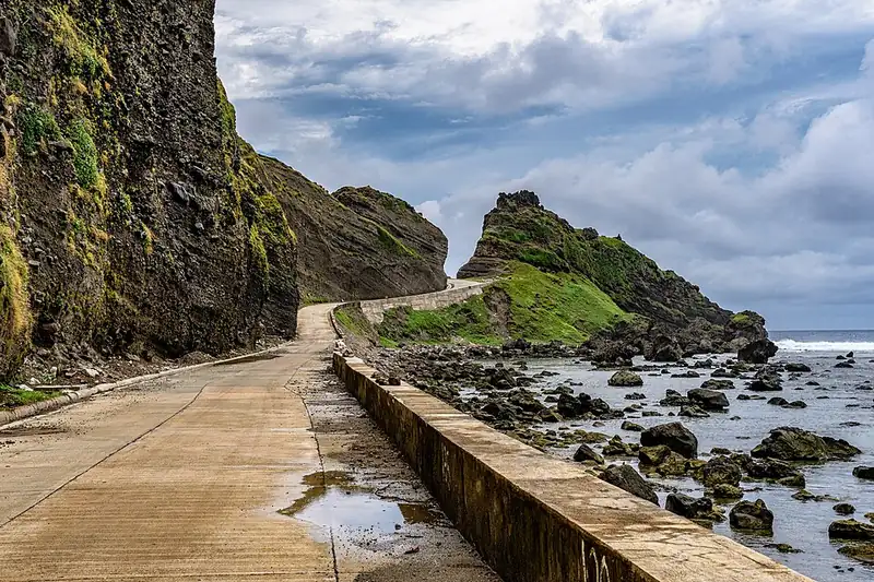 The coastal road climbing toward the Alapad hills and rock formations, Batan Island