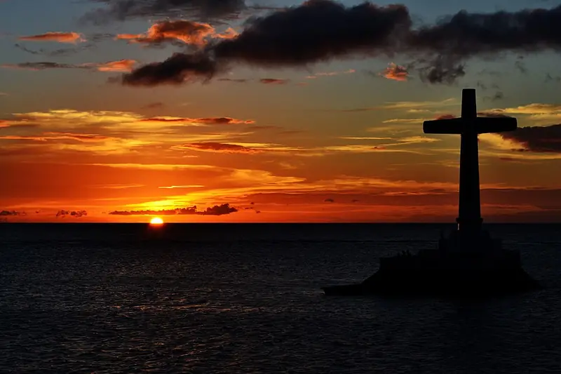 The cross marking the Sunken Cemetery against a sunset sky