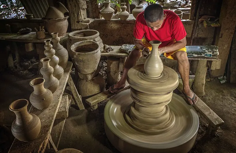 A potter shaping a burnay jar on a wheel in Vigan