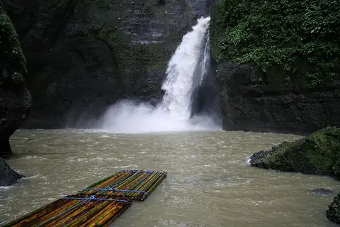 Pagsanjan Falls pouring into a pool, with bamboo rafts in front