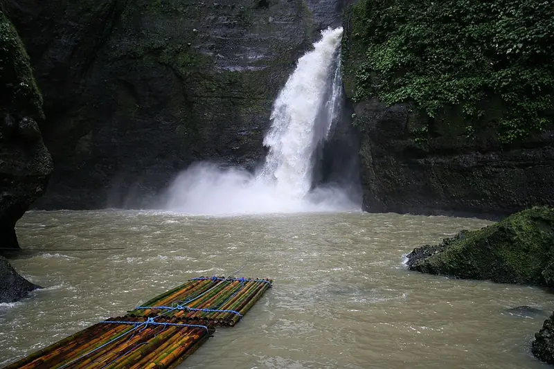 Pagsanjan Falls pouring into a pool, with bamboo rafts in front